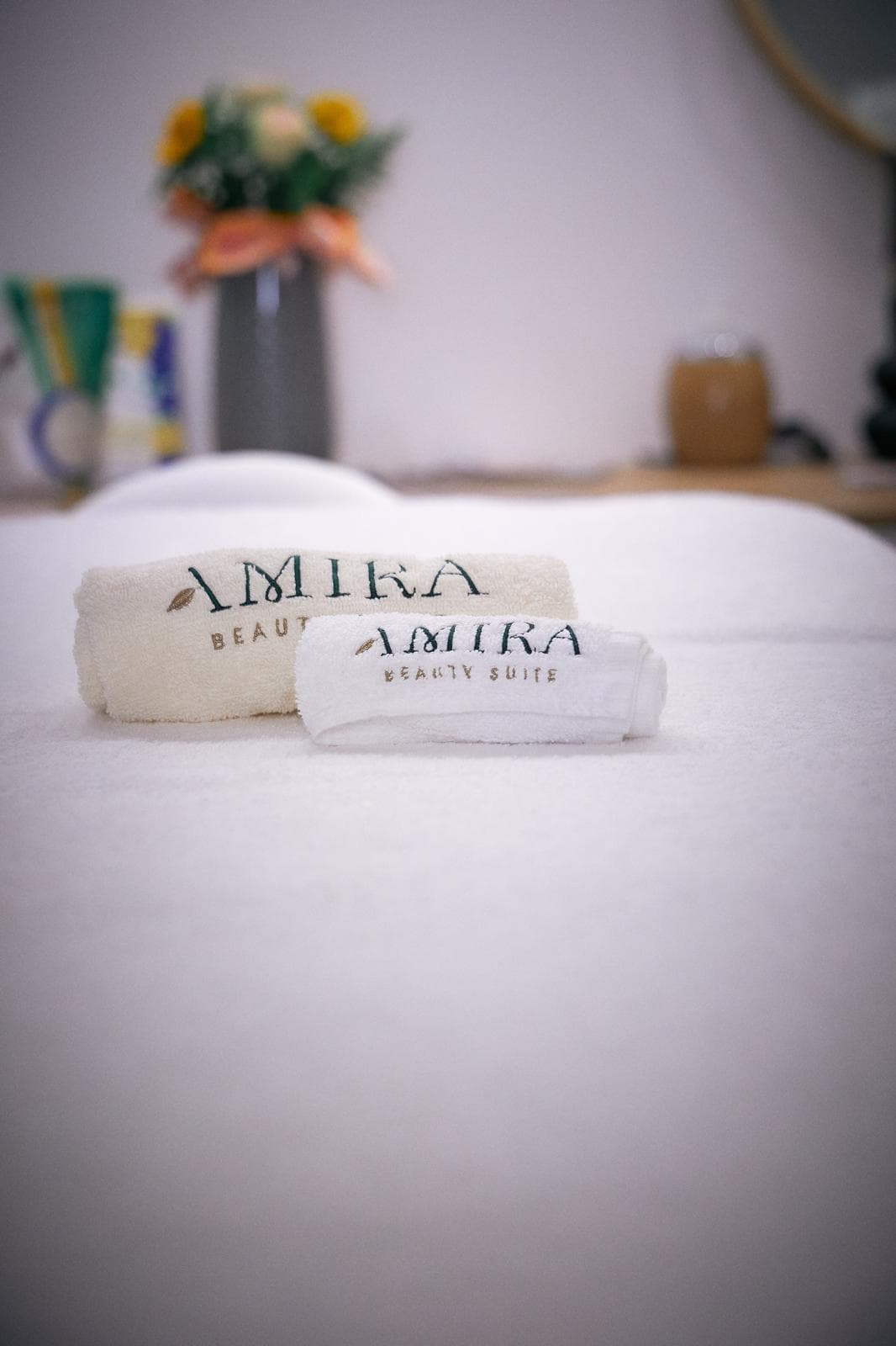 Due asciugamani con il ricamo Amira Beauty Suite piegati sul lettino