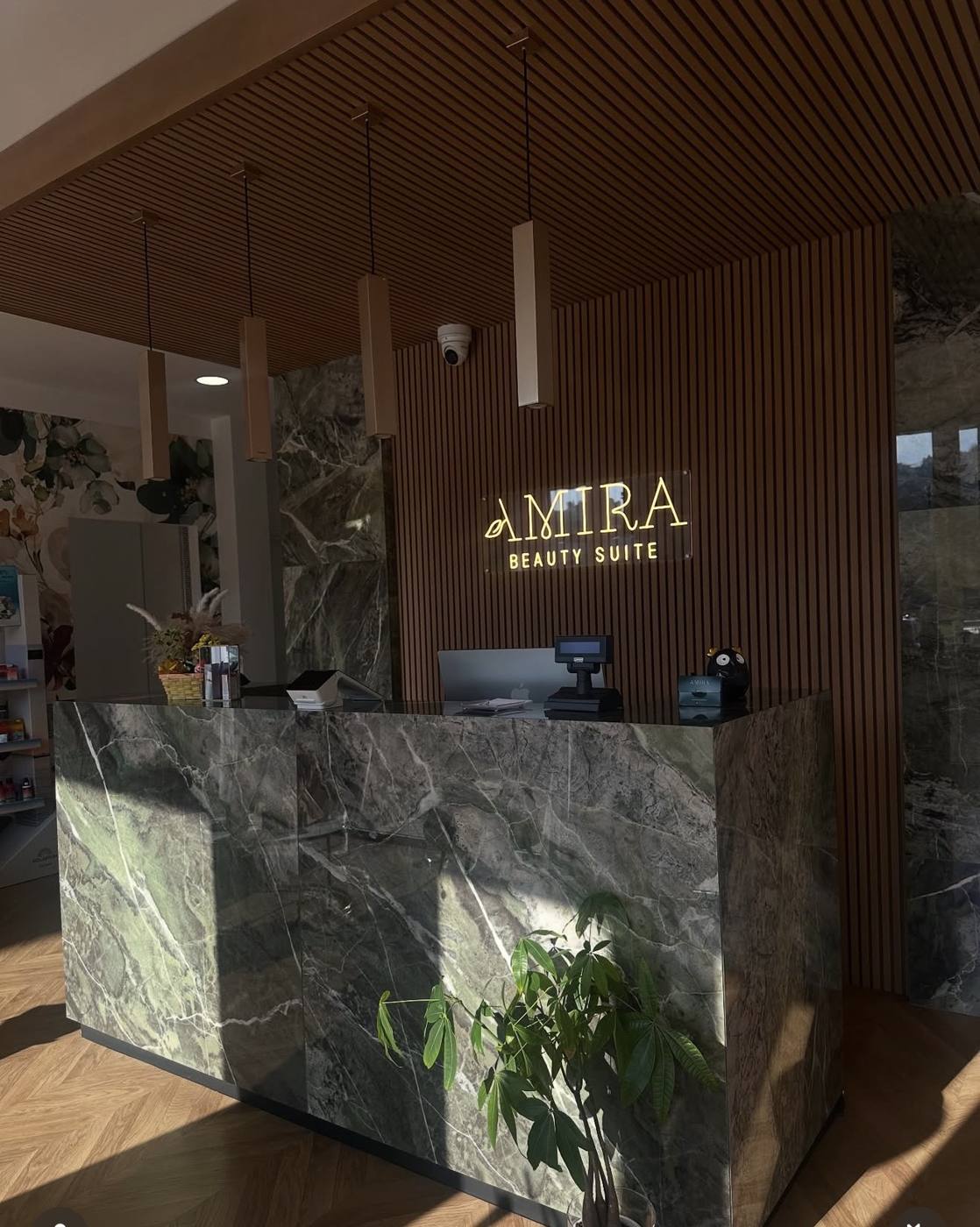 La reception in marmo verde con l'insegna luminosa Amira Beauty Suite